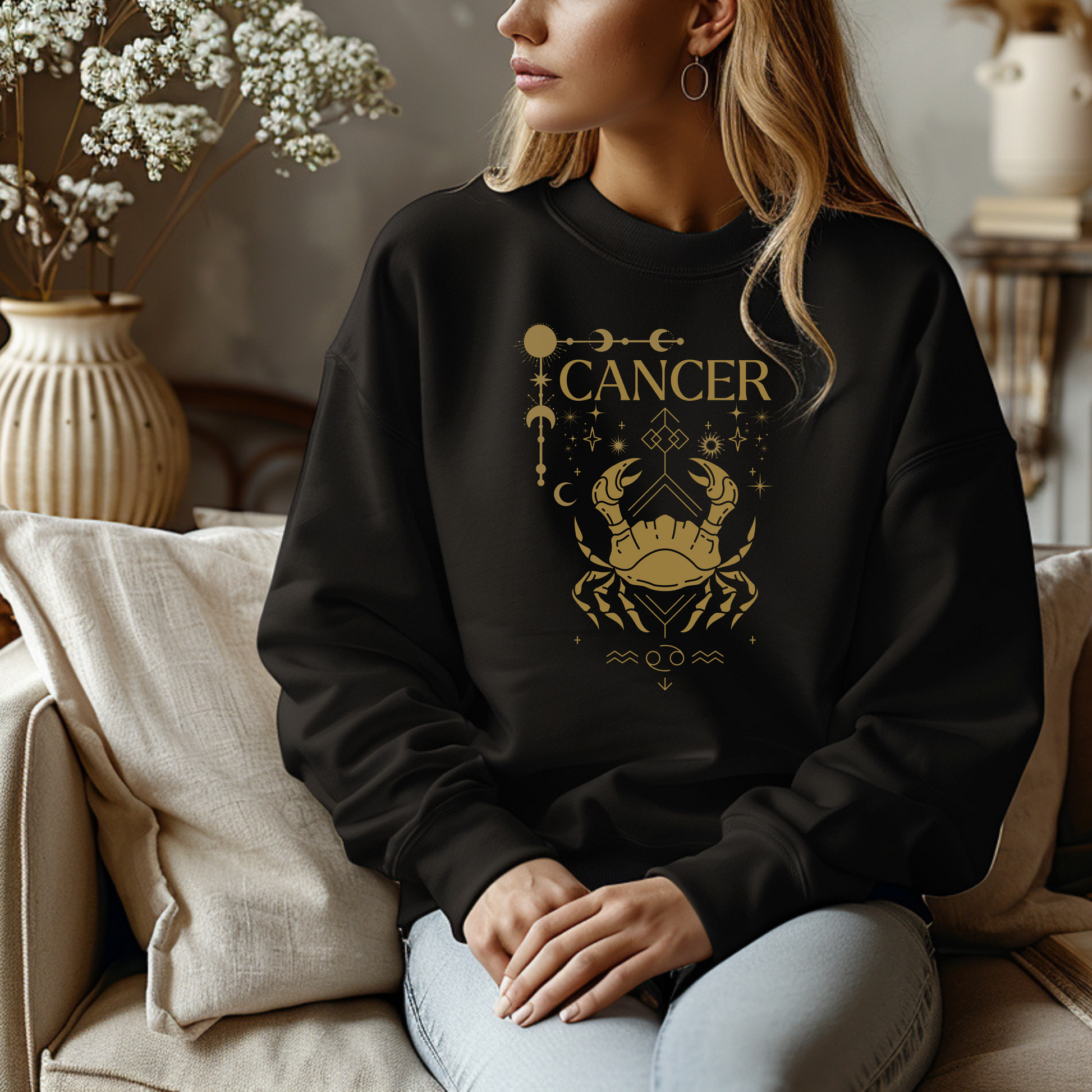 Black sweatshirt featuring a Cancer zodiac design in a brownish-gold color. The central illustration shows a stylized crab with intricate celestial symbols, stars, and decorative accents surrounding it. The word 'Cancer' is displayed above, and the Cancer zodiac symbol appears below, giving the design a mystical and astrological aesthetic.