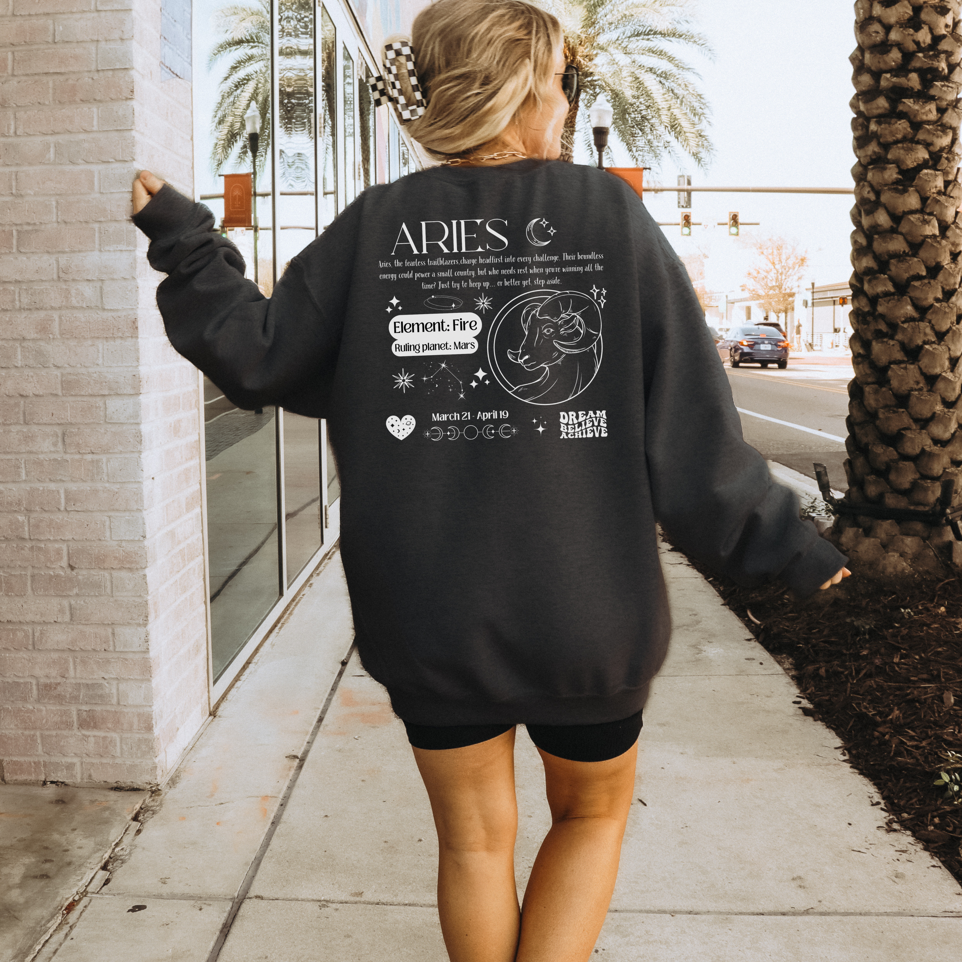 Black Aries sweatshirt with whitezodiac design featuring Aries symbol, Fire element, ruling planet Mars, and Aries traits text on the back.