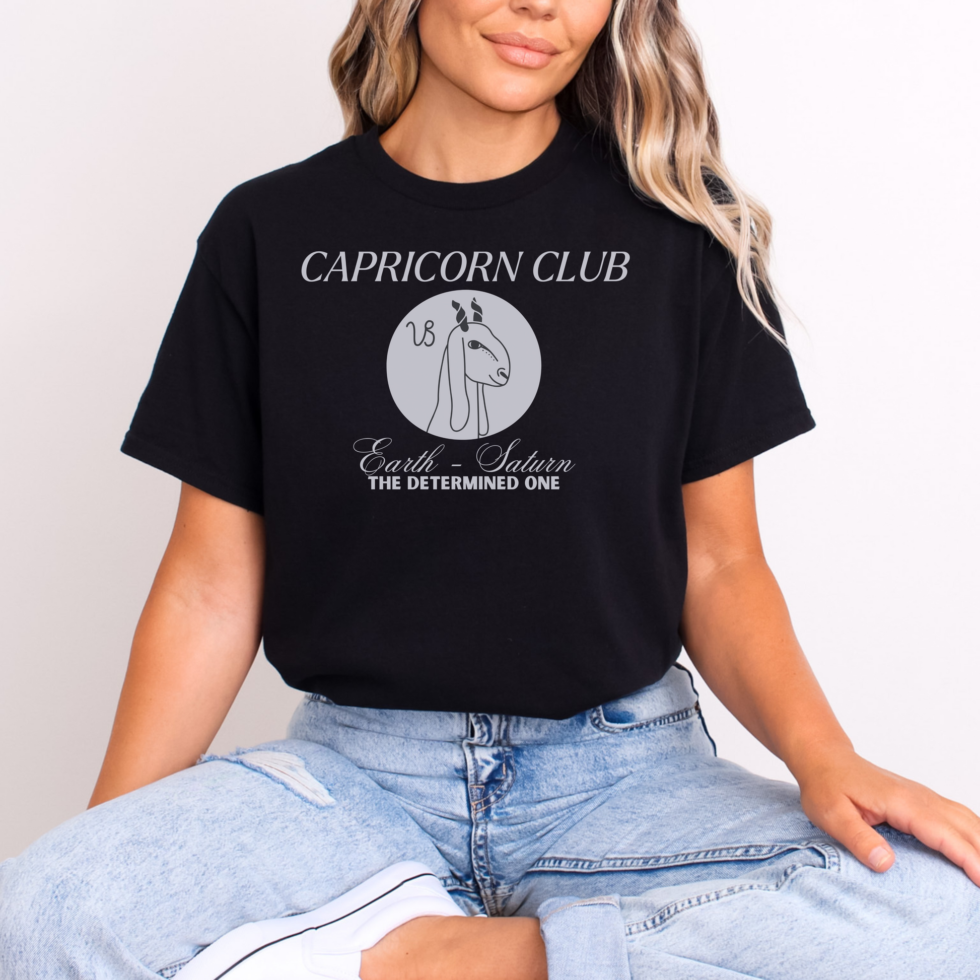 Front of black Capricorn-themed t-shirt with 'Capricorn Club' text, Capricorn symbol illustration, and phrase 'Earth - Saturn, The Determined One.