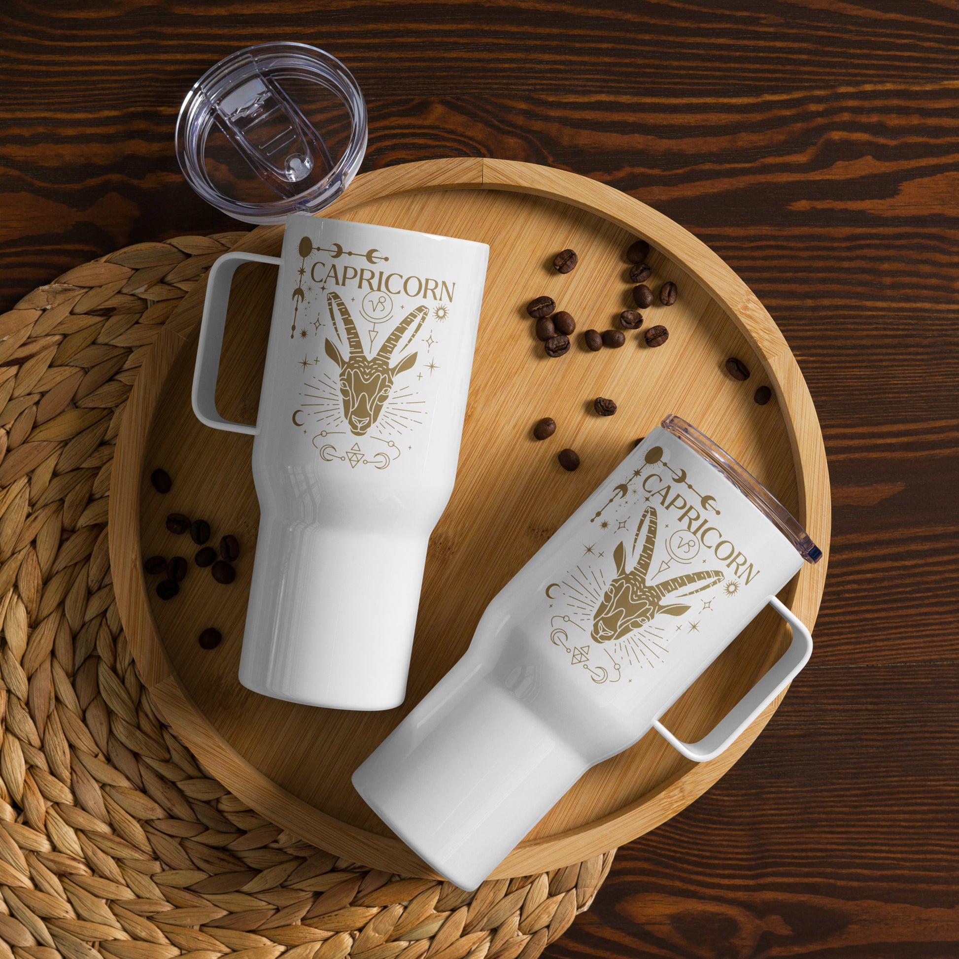 White Capricorn-themed travel mug with handle featuring a brownish-gold illustration of a goat symbol with celestial and ornate details.