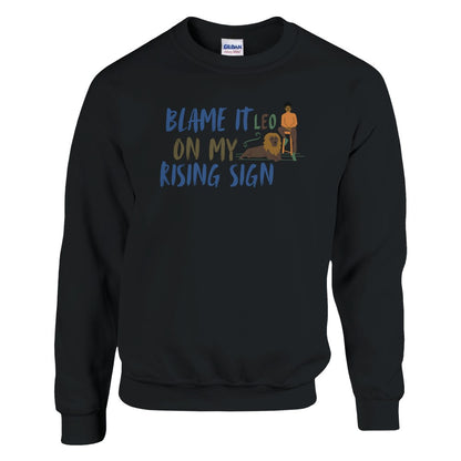 Front of black sweatshirt with Leo-themed design, text 'Blame It On My Rising Sign' featuring a person and a lion illustration.