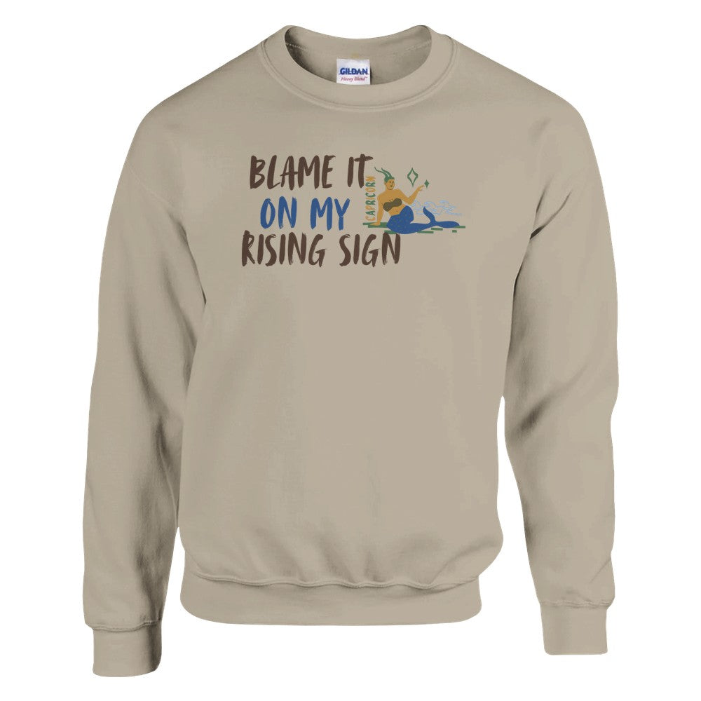 Front of sand Capricorn-themed sweatshirt with 'Blame It On My Rising Sign' text and illustration of Capricorn zodiac symbol.