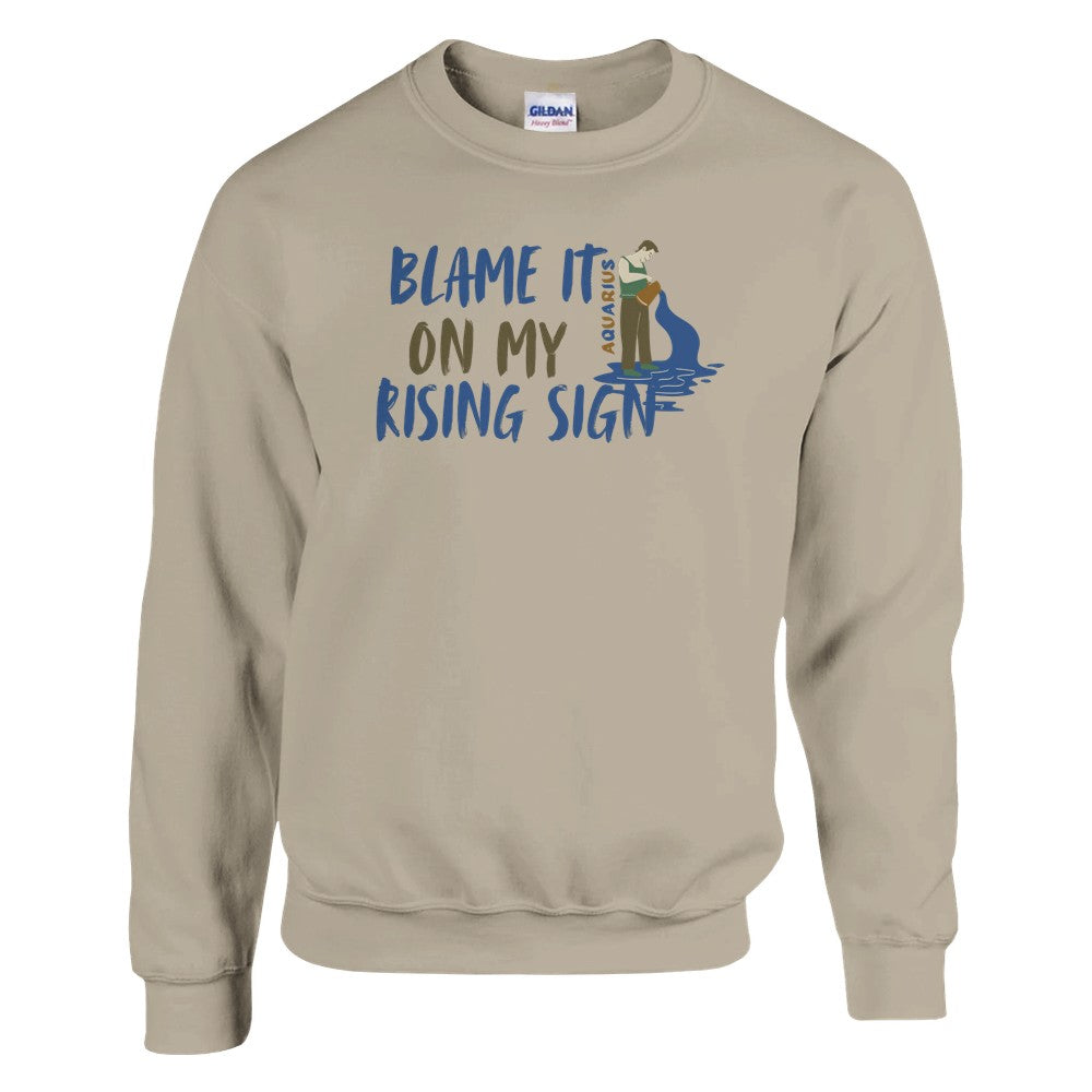 Sand Aquarius sweatshirt with 'Blame It On My Rising Sign' text and colorful Aquarius water-bearer illustration in blue and brown tones.