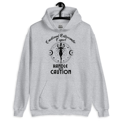 Sport grey hoodie featuring a Cancer zodiac-themed design with the phrase 'Emotional Rollercoaster Expert' at the top and 'Handle With Caution' at the bottom. The central illustration depicts a stylized figure surrounded by celestial symbols, including moons and stars, with a mystical, radiant backdrop in black accents.